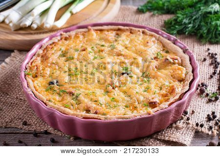 Traditional french quiche pie with chicken and mushroom on wooden table