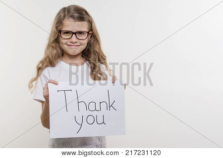 Girl child holding piece of paper with a word THANK YOU. White bakgrounde, copy space