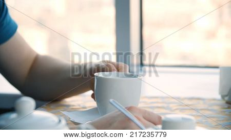 Male hand and white cup. Man holding blank cup, closeup. Closeup portrait of a young handsome man having a cup of coffee 4K