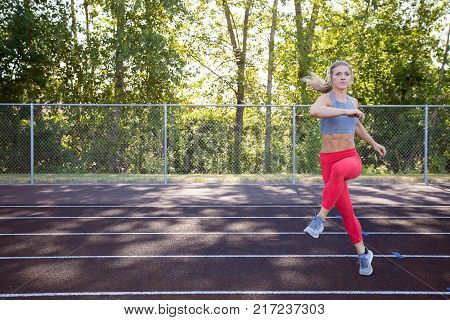 Grapevine exercise shown to the camera by a young female athlete while working out on an outdoor track in the summer.