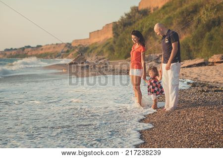 Family Together Enjoying Summer Vacation Time On Sandy Beach On Amazing Scene Of Sea Cliff And Sky W