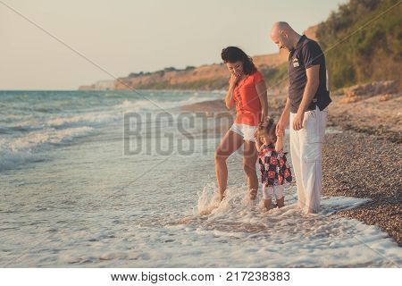 Family Together Enjoying Summer Vacation Time On Sandy Beach On Amazing Scene Of Sea Cliff And Sky W