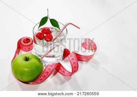 Green apple with measuring tape. Delicious home made drink with fresh berries in a glass. Healthy breakfast on a light background in a healthy diet concept and diet