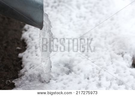frozen water in a drainpipe, with hanging icicles .