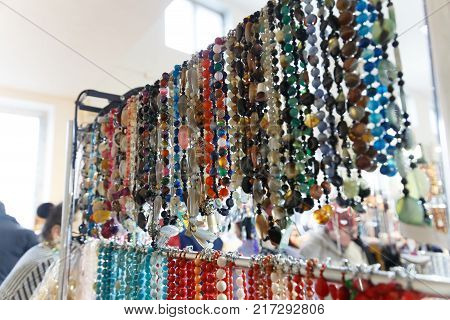 Beads baubles and bracelets with precious stones and pearls hang in a jewelry store shop