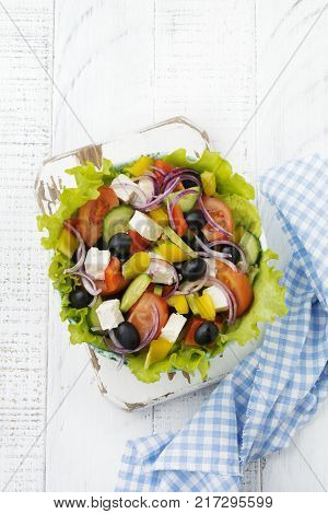 Greek salad in a ceramic plate on a white wooden background. Traditional Greek dish. Selective focus.Top view.
