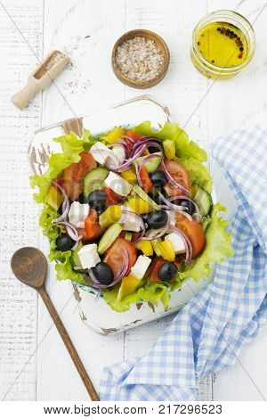 Greek salad in a ceramic plate on a white wooden background. Traditional Greek dish. Selective focus.Top view.