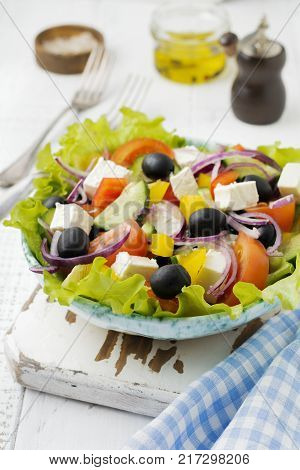 Greek salad in a ceramic plate on a white wooden background. Traditional Greek dish. Selective focus.Top view.