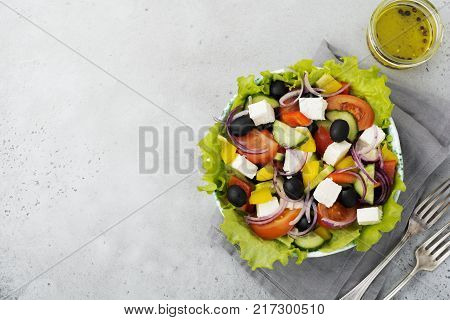 Greek salad in a ceramic plate on a white wooden background. Traditional Greek dish. Selective focus.Top view.