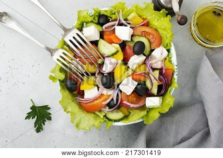 Greek salad in a ceramic plate on a white wooden background. Traditional Greek dish. Selective focus.Top view.