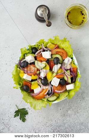 Greek salad in a ceramic plate on a white wooden background. Traditional Greek dish. Selective focus.Top view.