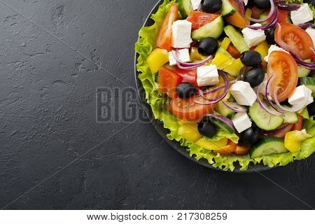 Greek salad in ceramic plate on gray concrete background. Traditional Greek dish. Selective focus.Top view.