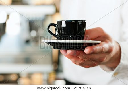 Coffeeshop - barista presenta caffè o cappuccino; primo piano sulla tazza