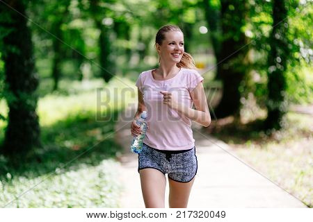 Beautiful jogging woman in nature staying fit and energetic
