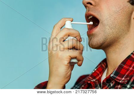 Sick young man using throat spray on color background. fresh breath. spray to eliminate bad breath. mint spray.