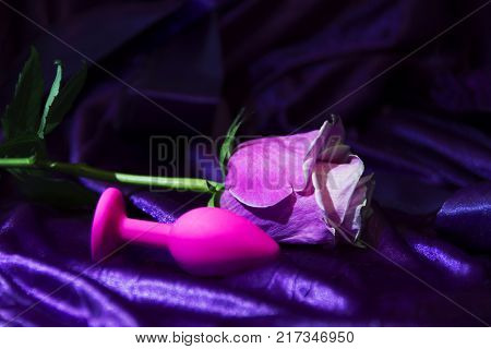 Silicone dildo Sex toy and a pink rose on a dark background