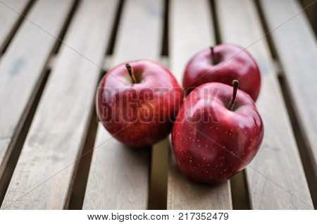Close up image of three ripe fresh apples on wooden planks