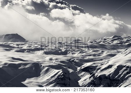 Snowy sunlight plateau and sky with clouds at winter evening. Caucasus Mountains Georgia region Gudauri. Black and white toned landscape.
