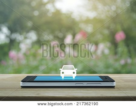 Taxi car flat icon on modern smart phone screen on wooden table over blur pink flower and tree Business transportation service concept