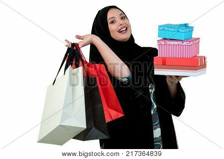 Happy young muslim woman with shopping bag and gift boxes isolated over white background.