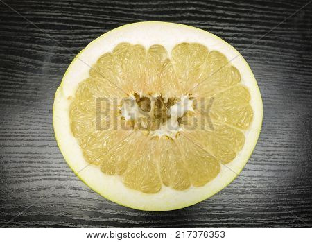 Split ripe fruit pomelo on a wooden dark table.