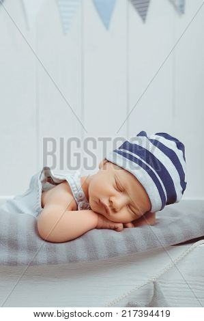 portrait of adorable infant baby in hat sleeping in wooden baby cot decorated with stars