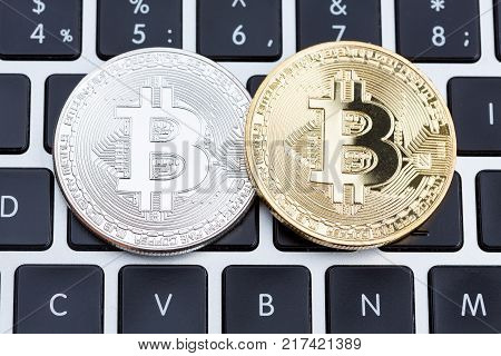 Golden and silver bitcoin coins on laptop keyboard. High resolution photo.
