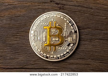 Close up of golden cryptocurrency yellow bitcoin on wooden background. High resolution photo.