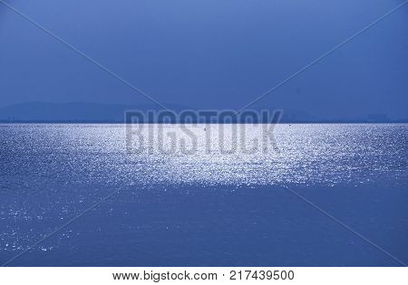 The reflection of the setting sun on the waters of Tai Lake Taihu outside of the three kingdoms city scenic area in Wuxi China in Jiangsu province.