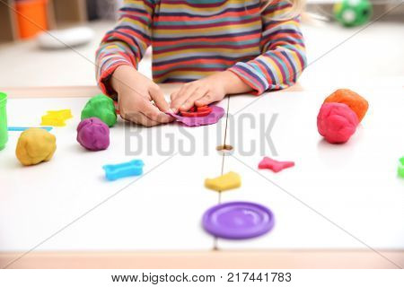 Little girl engaged in playdough modeling at table