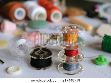 multicolored bobbins thread on the background of accessories for sewing close-up