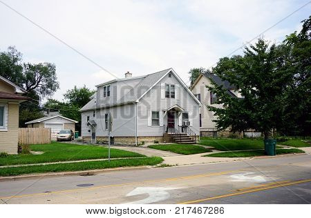 JOLIET, ILLINOIS / UNITED STATES - JULY 26, 2017: A small, single family, Cape Code style, two-story single family home, with a driveway and detached garage, on Plainfield Road in Joliet.