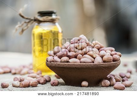 [arachis Hypogaea] Raw Groundnut In A Clay Bowl With Groundnut Oil On A Gunny Background.;