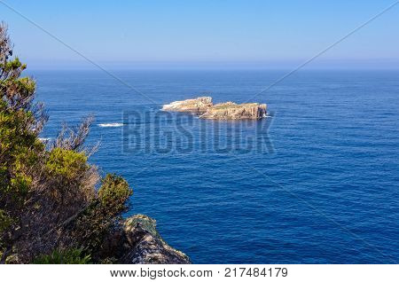 Two small rocky islands surrounded by blue water below 