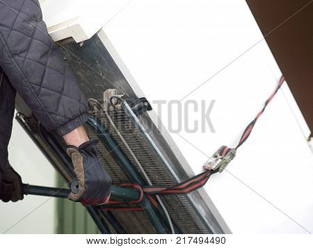 A man moving an old large strapped refrigerator on a trolley