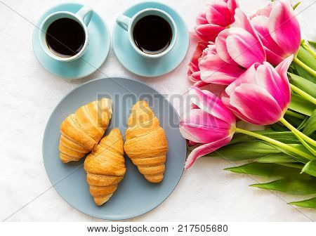 two cups of coffee, croissants and a bouquet of pink tulips, beautiful morning.