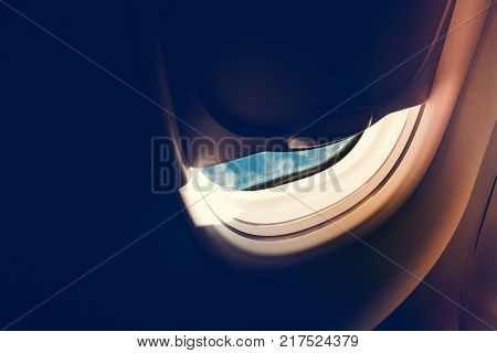 Airplane windows seat ajar with blue sky in the morning. Passenger open airplane window seat for look out to the blue sky with copy space for text.