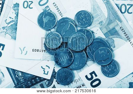 business finance saving and cash concept - close up of euro paper money and coins on table blue colored