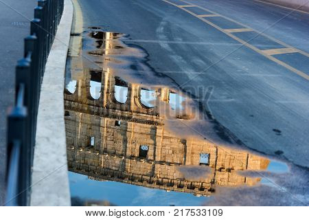 World famous Coliseum reflected on a puddle in Rome Italy