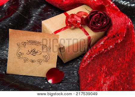 gift Packed in craftool paper with a dark red rose on shiny fabric