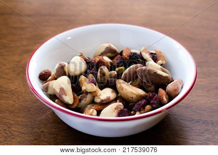 Bowl of nuts and dried fruits shot from a low angle, containing almonds, pistachios, brazil nuts, pecans, cranberries and dried cherries. Food rich in proteins, antioxidants and essential nutrients act as a healthy snack.