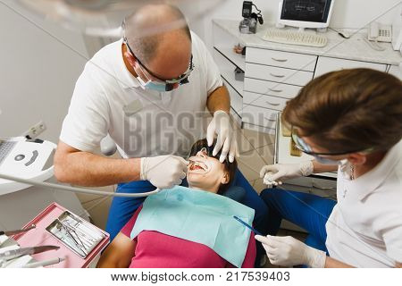 Process Of Preparing And Installing Dental Ceramic Crown. Male Professional Dentist And Female Assis