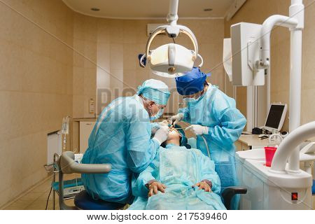 Process Of Preparing And Installing Dental Ceramic Crown. Male Professional Dentist And Female Assis