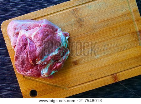 Meat piece on wooden cut board. Kitchen table top view photo. Raw meat preparing for cooking. Beef or pork fillet closeup. Steak recipe or cooking book image. Choosing meat for dinner. Wood cutboard