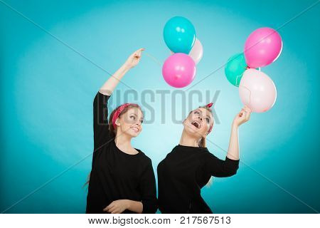 Memory of childhood and forgotten dreams. Two cute lovely retro styled women behave like little girls. Adults trying to fly away by balloons to dream come true.