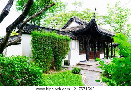 Vintage Chinese house with garden is sylvan day in Bangkok Thailand. This house are white wall and black vintage towards roof. Photo are big tree green grass and brick road on foreground.