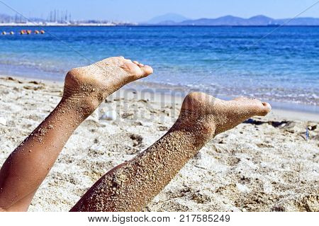 raised feets and legs on the beach