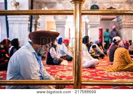 NEW DELHI INDIA - MARCH 18 2016: Horizontal picture of indian people of Sikh religion praying inside Gurudwara Sisganj Sahib located in New Delhi India.