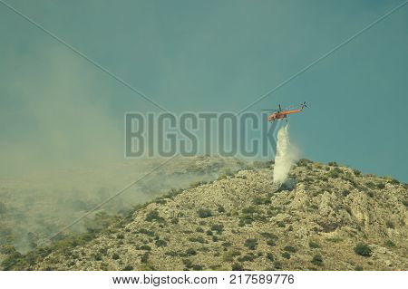 Fire helicopter extinguishes the fire on the hillside . Greece.