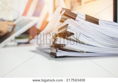 Paper stack Pile of unfinished documents on office desk related to business functions. Stack of business papers for Annual Report files on blur National flaguse tablet. Business offices concept